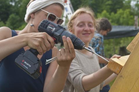 Jana (links) benutzt den Akkuschrauber an der Holzkonstruktion der Strohbrücke.