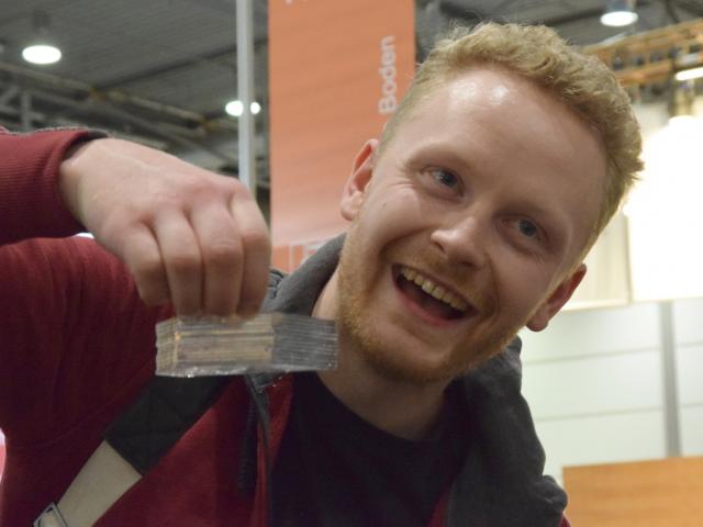 Aha-Effekt bei einem Messebesucher. | Foto: A. Theis Ein Messebesucher lernt die Kapillarkräfte von Wasser anhand von zusammenhaltenden Plättchen kennen und lacht. | Foto: A. Theis