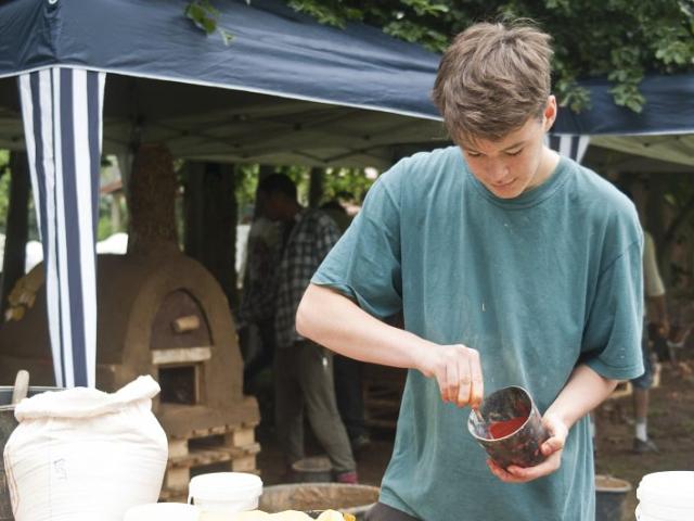 Anmischen von Lehmfarben für die äußere Gestaltung des Ofens. | Foto: Hendrik Silbermann (ARTWORKs) Ein Jugendlicher mischt Lehmfarben an, für die äußere Gestaltung des Ofens. | Foto: Hendrik Silbermann (ARTWORKs)