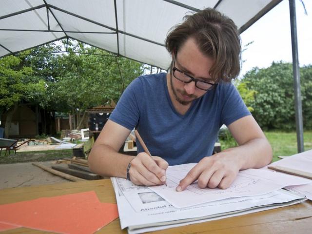 Planungen für die Komposttoilette werden gemacht. | Foto: Hendrik Silbermann (ARTWORKs) Planungen für die Komposttoilette werden gemacht. Ein junger Mann sitzt mit Unterlagen am Tisch. | Foto: Hendrik Silbermann (ARTWORKs)