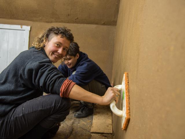 Glättung des Putzes. | Foto: Hendrik Silbermann (ARTWORKs) Glättung des Putzes durch eine fröhliche Teilnehmerin. | Foto: Hendrik Silbermann (ARTWORKs)